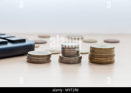 3 Stapel von Münzen und einen Rechner auf dem Tisch Stockfoto