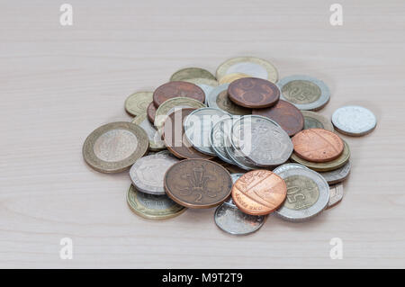 Eine Handvoll Münzen verschiedener Länder, Farbe, Würde und Größe liegen auf dem Tisch verstreut. Stockfoto