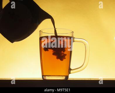 In einem durchsichtigen Glas Tee schüttete Milch aus einem Krug. Tea Party. Close Up. Stockfoto