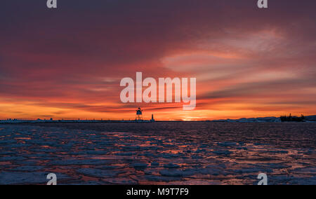 Sonnenuntergang über den Lake Superior im Winter am Leuchtturm in Grand Marais, Minnesota. Stockfoto