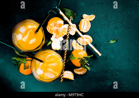 Erfrischender Cocktail mit Mandarinen, Saft und Eis in zwei Gläser auf einem schwarzen Hintergrund, alkoholische Getränke, Kopie Raum Stockfoto