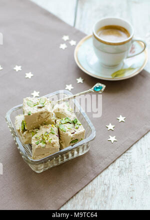 Traditionelle östliche Dessert - halva Pistazien und Tasse Kaffee. Arabische Spezialitäten auf hölzernen Tisch. Turkish Delight Konzept. Stockfoto