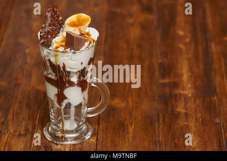 Eis Schokolade Cocktail in Glas mit Sirup, Banane, Süßigkeiten und andere Leckereien, Nahaufnahme Stockfoto