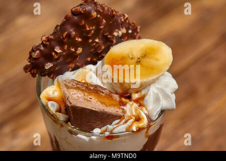 Eis Schokolade Cocktail in Glas mit Sirup, Banane, Süßigkeiten und andere Leckereien, Nahaufnahme Stockfoto