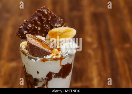 Eis Schokolade Cocktail in Glas mit Sirup, Banane, Süßigkeiten und andere Leckereien, Nahaufnahme Stockfoto