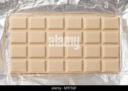 Ganze bar von milchig weiße Schokolade in einem offenen Metallic Folie Verpackung Stockfoto