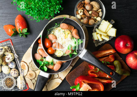 Deutsch Gesundheit Frühstück für zwei. Spiegeleier mit Würste in einer Pfanne mit Gewürzen und frischem Gemüse. Stockfoto