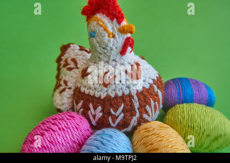 Frohe Ostern Symbole - aus Gewirken Henne und bunte Ostereier Dekoration, grüner Hintergrund, Platz für Kopieren, Text, Worte. Stockfoto