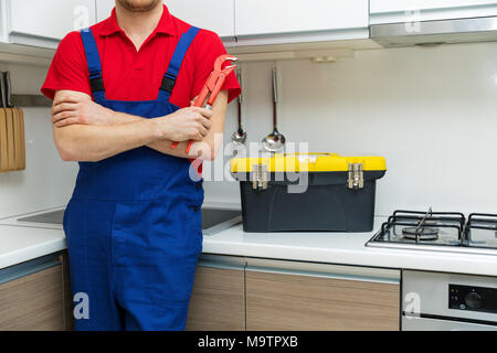 Klempner mit Schlüssel in der Hand in der heimischen Küche Stockfoto