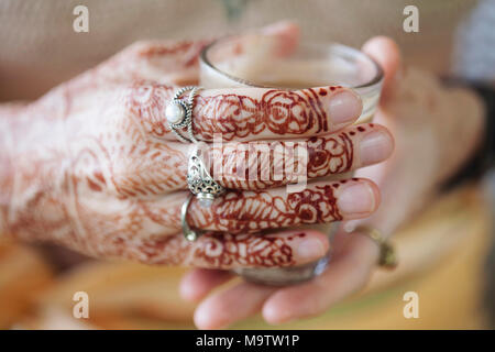 Weibliche Hände dekorativ durch Henna mit Tasse Masala Tee farbige Stockfoto