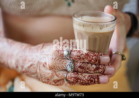 Weibliche Hände dekorativ durch Henna mit Tasse Masala Tee farbige Stockfoto