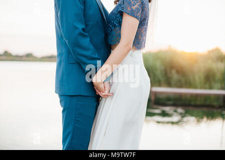 Für den Bräutigam, die Braut, die Hand auf den Sonnenuntergang. Bräutigam und Braut. Coupé von Liebhabern. Mann und Frau halten sich an den Händen. Stockfoto