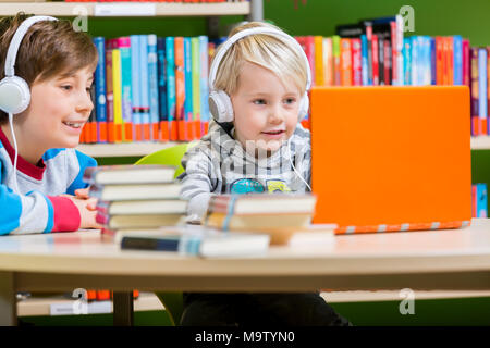 Kinder in einer Bibliothek zu den Audiobüchern hören Stockfoto