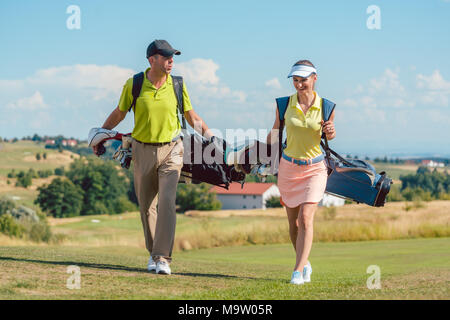 Glückliches Paar tragen Golf Outfits und Durchführung stehen Taschen Stockfoto