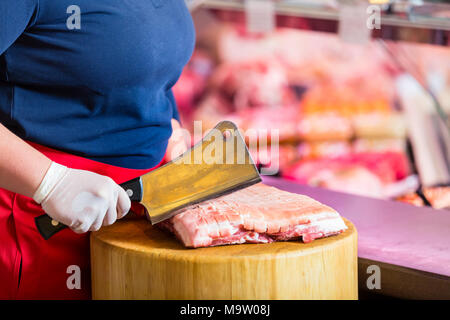 Metzger Frau Zerkleinern von Fleisch auf einem Block Stockfoto