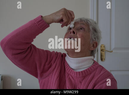 Ältere Frau, Augentropfen in trockene Augen, damit Sie sich wohl fühlen Stockfoto