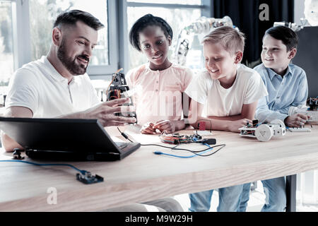 Reifen Lehrer zeigen neugierig Kinder seine neue Schöpfung Stockfoto
