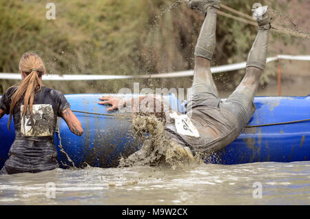 Menschen, die an einer Schlamm laufen Veranstaltung klettern über Objekte und sehr matschig, Stockfoto