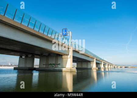 Die Zeeburgerbridge nach Amsterdam IJburg über das gefrorene Wasser der Nieuwe Diep vom Diemerzeedijk genommen. Stockfoto