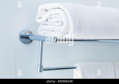 Nahaufnahme der gefalteten weißen Badezimmer Handtücher auf dem Regal in einer weißen Bad in der Nähe der Dusche, gut für sauber und frisch Thema oder Konzept aktualisieren Stockfoto