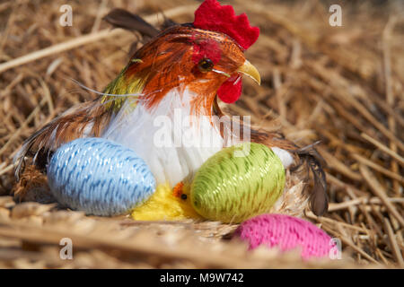 Frohe Ostern. Ostern Küken Dekoration in einem Nest Luken bunte Ostereier. Heu und getrocknete Roggen Glocken Hintergrund. Stockfoto