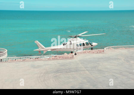 Helikopter fliegt über dem azurblauen Meer Stockfoto