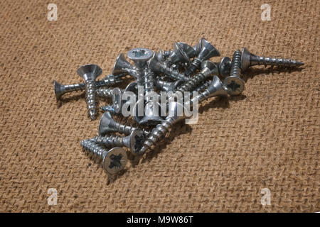 Stapel der Schrauben auf Holz- Hintergrund. Blechschrauben aus Stahl, Eisen Schraube, Schrauben als Hintergrund, auf einer hölzernen Oberfläche. Stockfoto