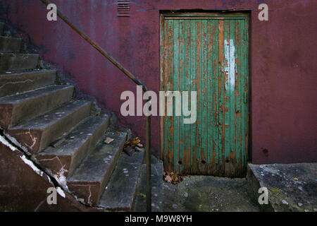 Grüne alte Tür auf magenta Wand mit Treppen an der Seite Stockfoto