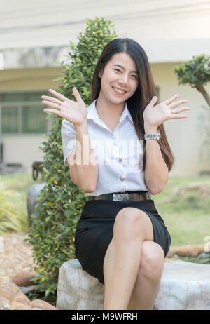 Nette junge asiatische Frau in Uniform student Lächeln in Garten, Glücklich und Konzept entspannen Stockfoto