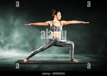 Fit athletische junge Frau Demonstration der Krieger 2 Stellen im Yoga longieren Stretching vorwärts mit gerade ausgestreckten Arme Stockfoto