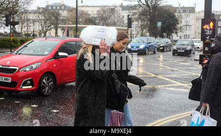 Crawley, UK, 29. März 2018 - eine junge Frau versucht, auf einem stumpfen blustery Tag trocken in Brighton heute mit kühlen verunsichert Wettervorhersage für das kommende Osterfest Bank Holiday Wochenende Credit: Simon Dack/Alamy leben Nachrichten Stockfoto