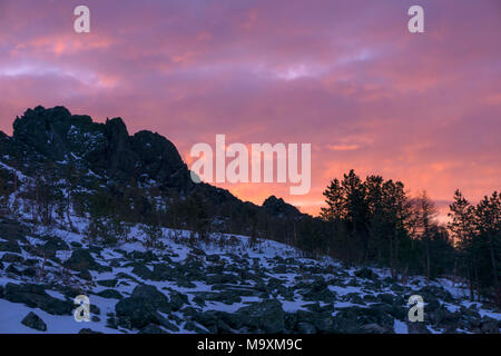 Hell Crimson Dawn oder Sonnenuntergang über einem frostigen Rock Ridge Stockfoto