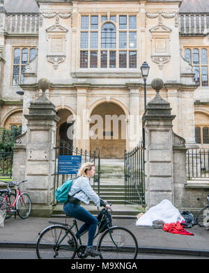 Eine obdachlose Person schläft auf dem Bürgersteig vor dem Eingang zum historischen Fakultät der Universität in der Stadt Oxford, England, an einem Wintertag Stockfoto