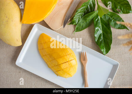 Mango Slices auf weiße Platte mit frischer Mango und Blätter, Ansicht von oben Bild Stockfoto