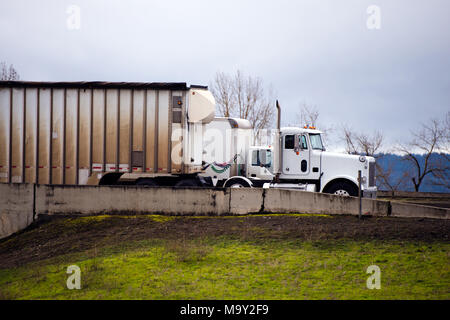 Anderen Tag cab big Rigs halb Lkw für den gewerblichen Lieferung von kommerziellen Ladung gehen Seite an Seite auf der Autobahn die Ausfahrt hinter der konkreten Fe Stockfoto