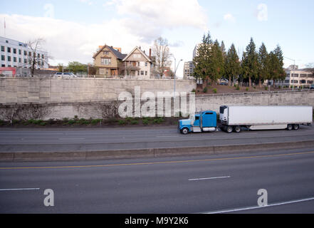 Blau klassische amerikanische Big Rig halb LKW-Flotte für die Fernbeförderung Lieferungen von Lebensmitteln mit Kälte- Auflieger auf der breiten Autobahn gehen durch Stockfoto