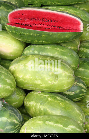 Große Gruppe der Wassermelone vertikales Format mit Samen geschnitten. Öffnen Sie im auf einen Haufen gestapelt Hoch aus eine volle Ernte von Melonen ein Sommer Obst vertikale zu sehen Stockfoto