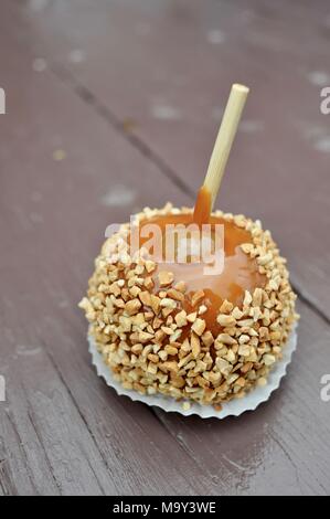 Zerkleinerte Erdnüsse in Karamell überdachten großen frischen Apfel auf braune Holzbank außerhalb des historischen 1837 Franklin Cider Mill, Bloomfield Hills, Michigan, USA. Stockfoto