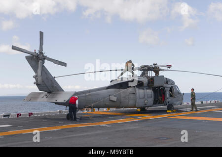 180326-N-NB 142-003 PAZIFISCHEN OZEAN (26. März 2018) Matrosen und Marines führen Sie Kontrollen vor dem Flug auf einem MH-60S Seahawk Hubschrauber zum "Blackjacks" der Hubschrauber Meer Combat Squadron (HSC) 21 beigefügt, das auf dem Flugdeck des Wasp-Klasse amphibisches Schiff USS Essex (LL 2) während einer amphibischen Squadron und Marine Expeditionary Unit (MEU) Integration (PMINT) Übung. PMINT ist ein Training Entwicklung zwischen Essex Amphibious Ready Gruppe und 13 MEU, Matrosen und Marines als zusammengehörige Einheit in der Vorbereitung für die bevorstehende Bereitstellung zu trainieren. (U.S. Marine Foto von Masse Kommunikatio Stockfoto