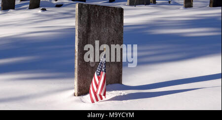 Grabstein sehr alt mit der amerikanischen Flagge im Winter, Schnee liegt auf dem Boden Stockfoto