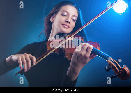 Schöne junge Frau spielt die Geige auf dunkelblauem Hintergrund. Studio shot Stockfoto