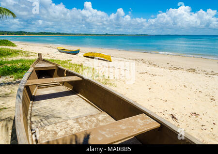 Innenraum eines Holz- Kanu im Vordergrund und im Hintergrund einen schönen und sonnigen Strand mit Kanus am Strand, Himmel voller Wolken und ein blau Stockfoto