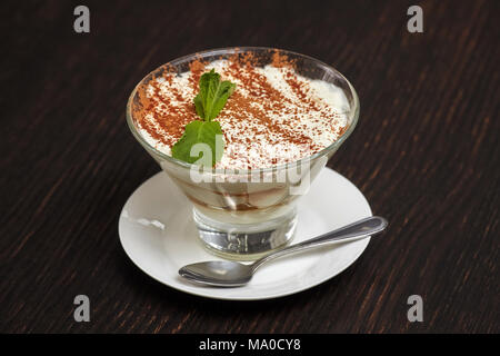 Tiramisu Creme Kuchen Dessert im Glas mit Minze auf schwarzem Holz- Hintergrund Stockfoto
