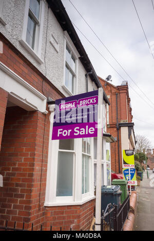 Lila Ziegel Immobilien zum Verkauf Zeichen auf einem typischen britischen Straße mit Reihenhäusern. Stockfoto