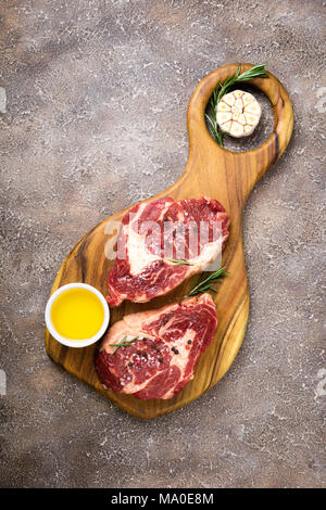 Rohes Fleisch. Rohes Rindfleisch Steak auf einem Schneidebrett mit Rosmarin und Gewürze, Ansicht von oben Stockfoto
