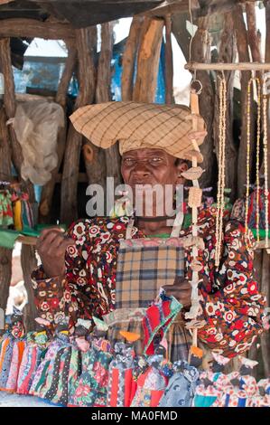 Herero Frau in traditionellen deutschen kolonialen Kleid und Kuh - Horn hat vor Ihr Souvenir dolls Stall, Namibia Afrika. Stockfoto