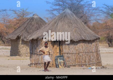 Lokale Frau in der Nähe von einem typischen strohgedeckten afrikanischen runde Hütte in Botswana. Stockfoto