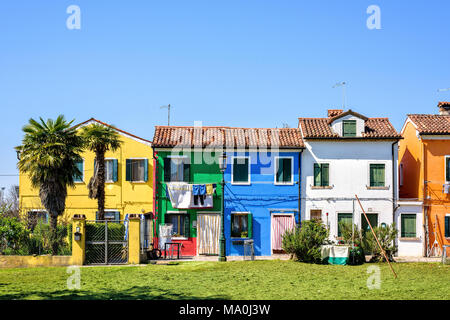 Tageslicht zu lebhaften komplementäre bemalte Gebäude mit grünen Gras vor. Der strahlend blaue Himmel. Negative Kopie Platz, Platz für Text. Burano Stockfoto