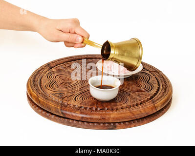 Sie ist mit einem schwarzen Kaffee aus türkischen Kaffee Topf (a jazve oder ein ibrik), und gießt es in türkischen Kaffee Tasse (a fildzan). Stockfoto