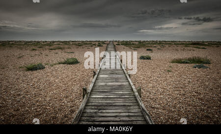 Die hölzernen Fußweg auf der Kiesstrand in Dungeness in Kent zum Meer führt. Stockfoto